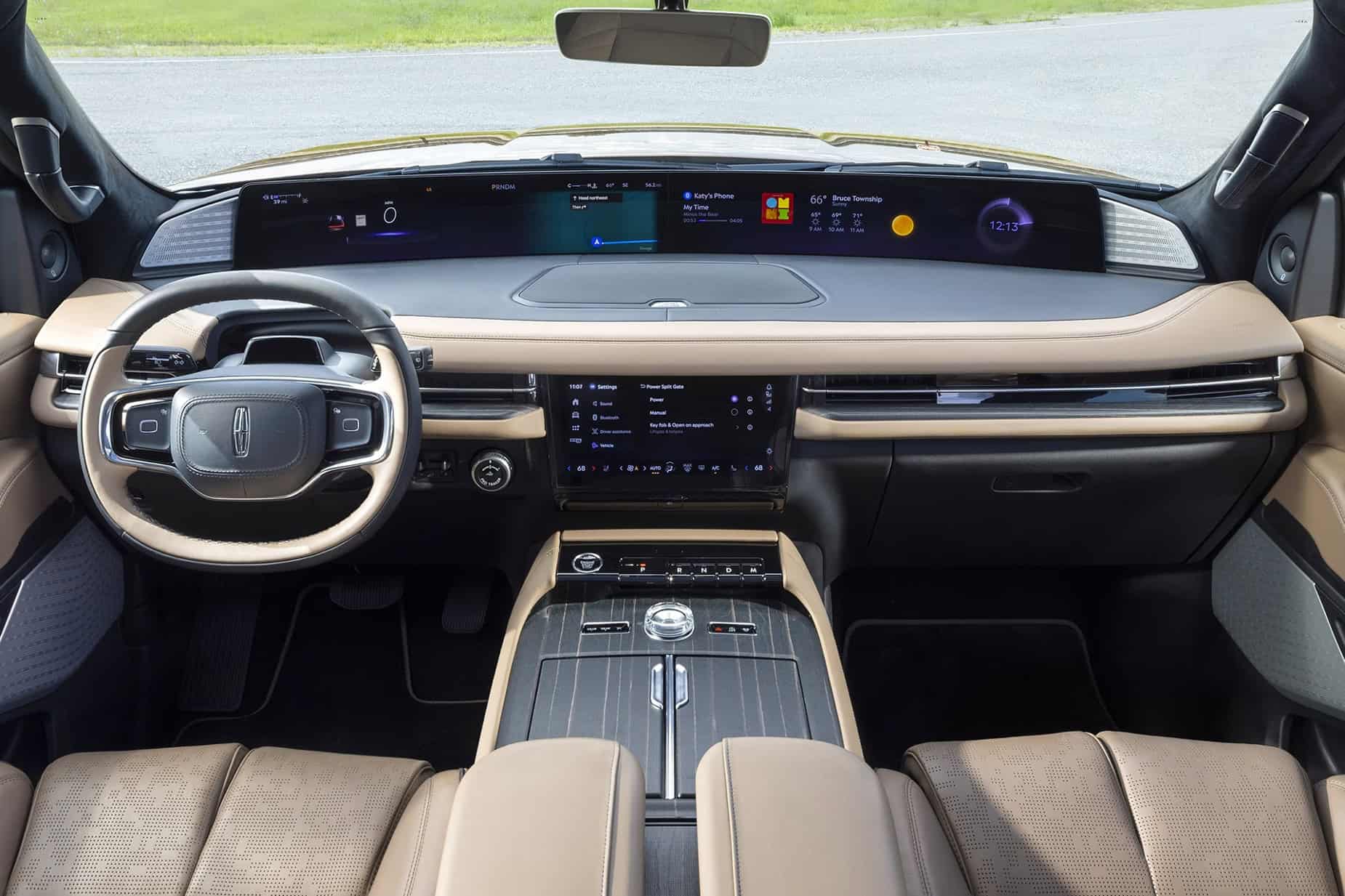 Symmetrical view of a Lincoln Nautilus interior from the rear seat. It features a massive 48-inch panoramic display stretching across the entire dashboard, an elliptical steering wheel, and a premium center console with wood accents and cream-colored leather.